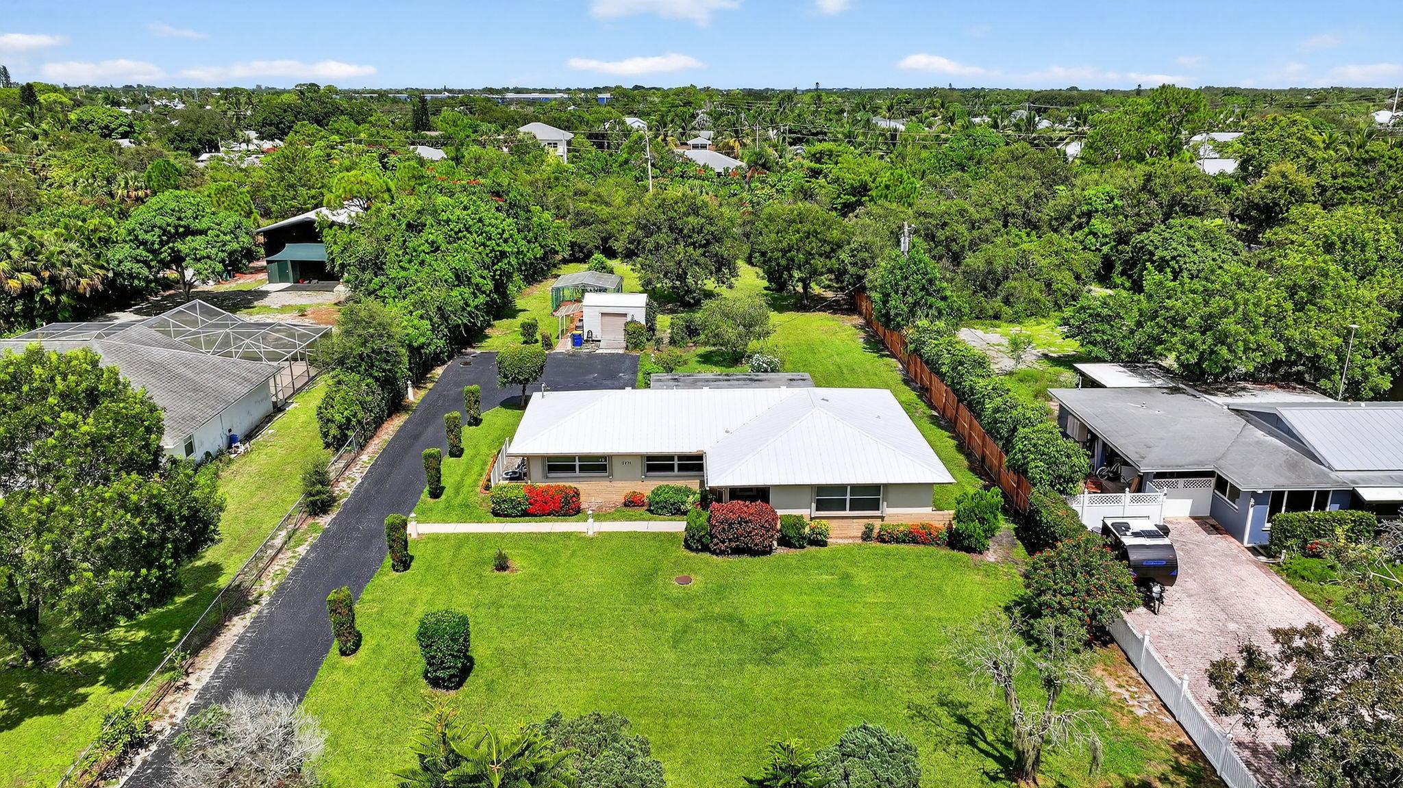 WOW~ What a property!!! Huge Oversized 1 Acre in the heart of Stuart & Rocky Point! This fabulous 2-Bedroom 2-Full Bathroom, Solid CBS Home has a Large Wrap Around Driveway to the 1 car-garage behind the house. Lush Lawn & Mature Trees. 2009 Metal Roof, 2021A/C- Accordion Hurricane Shutters, Screened in Front Porch w/Beautiful Etched Glass Front Door leading into this solid built home! Open Floor Plan. Spacious Kitchen w/Large Panoramic Windows, Wood Cabinetry, Granite Countertop & Eat-in Bar w/Pantry, White Appliances. French Doors leading to the enclosed Florida Room w/split ac unit. Separate Detached Shed, Greenhouse, Landscape Lighting, 6' Wood Fence on East side. Lg Concrete Patio. Backyard extends to the power lines. NO HOA, Room for Pool and All your toys!!! A MUST SEE!