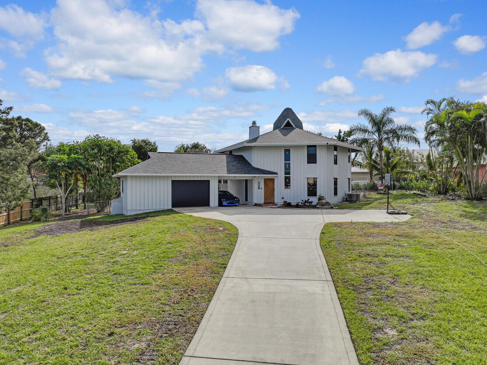 Nestled on a huge lot on the scenic bluffs of Hobe Sound, this stunning custom-built 4/2 home with New Roof in the prestigious Papaya Village offers a perfect retreat for nature lovers. Set on over half an acre at the crown of the bluff, the home captures the beauty of its natural surroundings blending seamlessly with the landscape. Designed to embrace the soothing ocean breeze, the home's unique hexagonal layout and custom vented cupolas enhance airflow and natural light, helping it blend seamlessly with the environment. New sod, seeding and landscaping has just been installed to enhance the overall ambiance. Newer high end Smart Kitchen Appliances, Wrap around Patio and Balcony and an abundance of parking are added features of this home. Come see it today!