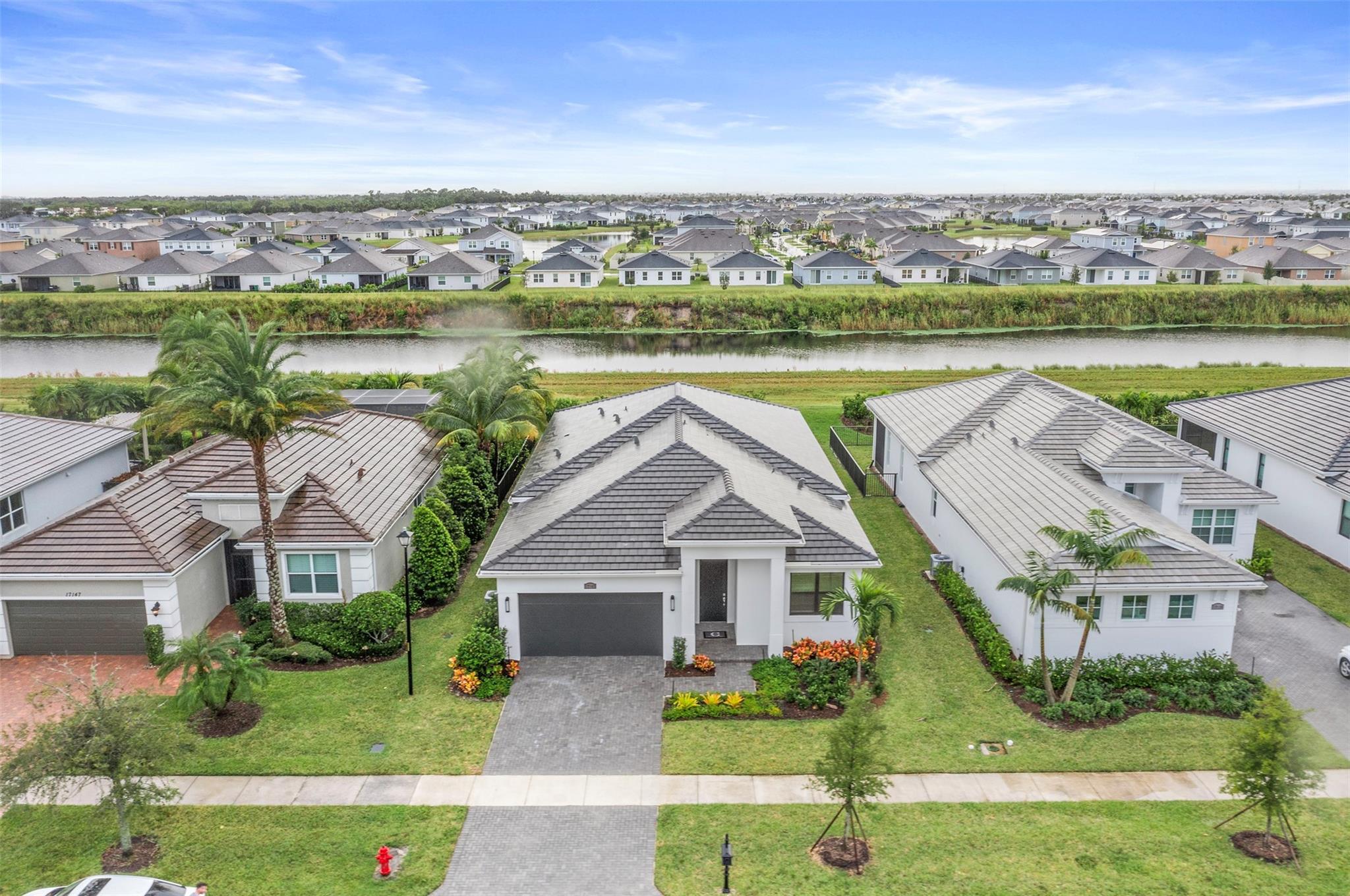 Perfect *Turn Key Home* offering lush tropical landscaping & plenty of privacy overlooking a private canal. *NO NEED TO BUILD* This 3BD/3BA, w/Flex room (office/gym) home boasts gorgeous upgraded features: Complete Hurricane Impact Windows & Doors, Laminate Wood Floors thru-out, Gourmet Kitchen with 42” White Cabinets w/Crown Molding & under Cabinet Lighting, a Quartz Island & Countertops w/plenty of space for Entertaining & Motorized Solar Blinds in great room. The Owner’s suite features a tray ceiling, Custom Motorized Cellular Blinds, Frameless Shower, a huge Walk-in closet that connects to the laundry room. This home located across from the clubhouse & fitness center offering 27-Court Pickleball, Tennis Courts, SmartFIT Training Center, Resort-Style Pools in PGA Verano Golf Community.