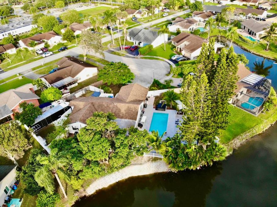INVESTORS ALERT! Exceptional waterfront property with outstanding rental and income potential. Numerous updates and remodels throughout. Features a private in-law/studio with its own entrance, plus an oversized primary bedroom that can easily be converted into an additional studio. Enjoy an oversized Florida room with tranquil lake views, a brand-new large Trex deck, and a spa. The expansive lot offers double fence doors for easy storage, accommodates up to 5 cars, a 30-ft trailer, and two 34-ft boats. Outdoor highlights include two large sheds, a fire pit, two avocado trees, and a mature mango tree producing fruit annually. The kitchen boasts an oversized pantry, and the primary bath is ready to be remodeled to your taste. Endless possibilities for investors or multi-generational living.