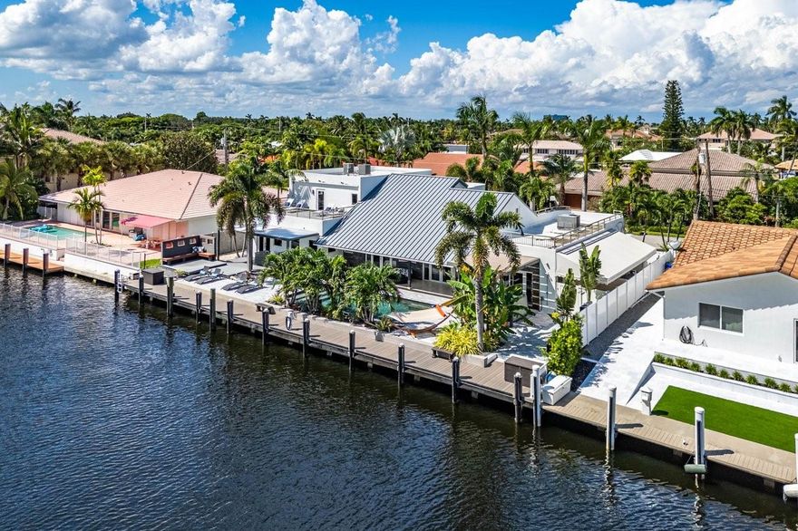 One of only 2 homes with 100' of waterfront in Coral Ridge Country Club. This waterfront home, in the highly sought after CRCC is only 4 houses from the Intracoastal and just blocks to Coral Ridge Country Club. Enjoy Intracoastal views and ocean breezes from the spacious upper balcony. The exterior upgrades are endless. Spectacular landscaping and landscape lighting, amazing water and fire features, just to name a few, elevate the outdoor living experience. A new roof in 2022, a whole house generator and water filtration system, natural gas, salt water pool conversion, hot tub, and new dock lighting power station add to the endless list of upgrades. New Brand new Outdoor Kitchen and Landscaping just completed. Priced to sell. Bring your buyers.
