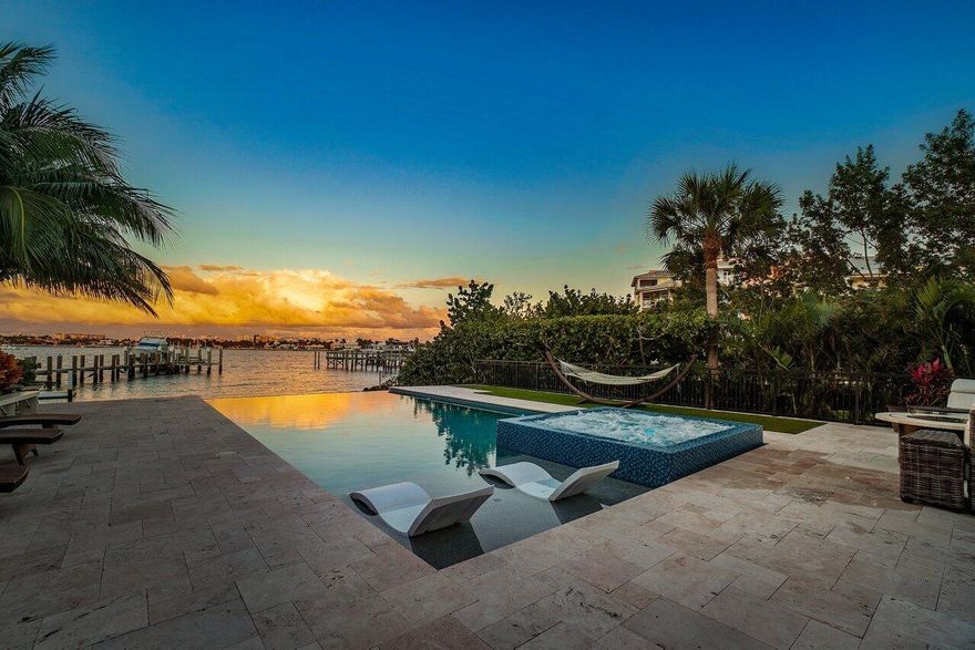 Experience waterfront luxury in this newly renovated direct Intracoastal home. Enjoy breathtaking views from the heated infinity-edge pool and spa, just above your private sandy beach. Inside, soaring 30-foot ceilings, marble floors, quartz countertops, Viking appliances, and designer finishes elevate every space. The grand primary suite features dual walk-in closets, a free-standing tub, and a private patio with panoramic water views. Updates include custom lighting, a quartz fireplace, custom closets, and Gray Malin wallpaper. A guest cottage with a kitchen sits off the gated courtyard. Impact windows, smart home technology, and a security system make it easy to monitor and control your home remotely. Dock your boat on the lift and walk to Old Key Lime House, Eau Resort, or the beach.