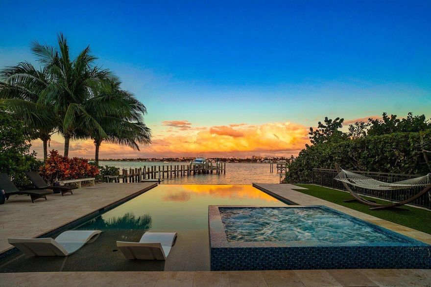 Experience waterfront luxury in this newly renovated direct Intracoastal home. Enjoy breathtaking views from the heated infinity-edge pool and spa, just above your private sandy beach. Inside, soaring 30-foot ceilings, marble floors, quartz countertops, Viking appliances, and designer finishes elevate every space. The grand primary suite features dual walk-in closets, a free-standing tub, and a private patio with panoramic water views. Updates include custom lighting, a quartz fireplace, custom closets, and Gray Malin wallpaper. A guest cottage with a kitchen sits off the gated courtyard. Impact windows, smart home technology, and a security system make it easy to monitor and control your home remotely. Dock your boat on the lift and walk to Old Key Lime House, Eau Resort, or the beach.