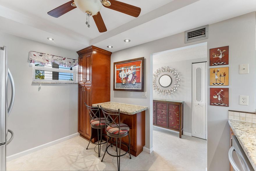 Welcome to this beautifully updated condo offering a perfect blend of style and comfort. The heart of the home is the stunning kitchen, featuring rich wood cabinetry, granite countertops, stainless steel appliances, and a convenient breakfast bar. The open-concept living area is bright and spacious, highlighted by sleek tile flooring and large sliding glass doors that fill the space with natural light.  Relax in the generous primary suite, featuring wood-look flooring, a ceiling fan, and a private en-suite bathroom with a modern vanity and a glass-enclosed shower. A second bedroom offers flexibility for guests or a home office, complete with ample closet space. Step out onto the screened-in balcony to enjoy peaceful views of the sparkling community pool and lush greenery—the perfect spot for your morning coffee.