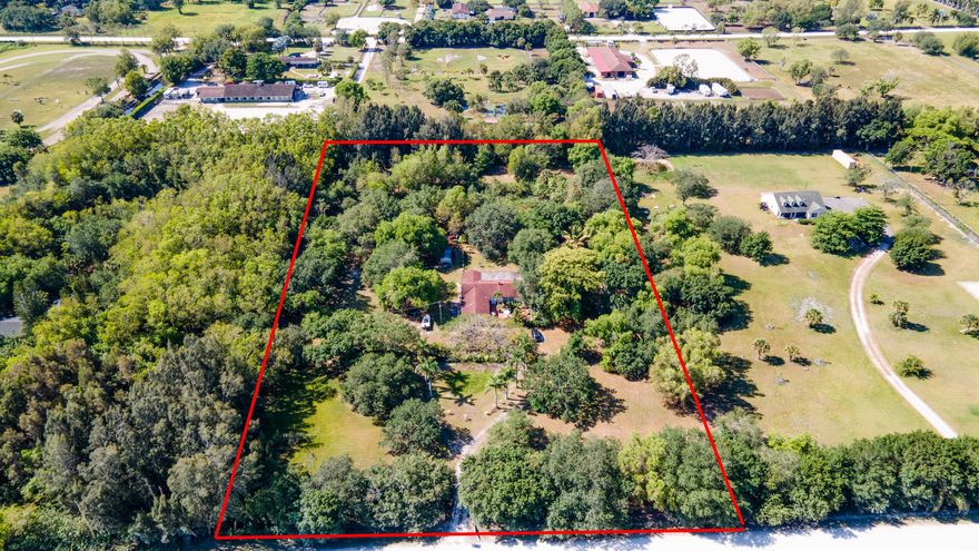 Discover the perfect canvas for your equestrian dream home in highly coveted Rustic Ranches subdivision of Wellington. This exceptional property spans 5 acres of prime equestrian land, offering a unique opportunity to design and build bespoke mansion tailored to the most discerning tastes. Included in this offering is a 2,986 sq ft home, ready to be transformed into a stunning residence that epitomizes luxury and comfort. Envision adding personalizes stables and paddocks, creating an idyllic environment for both horse and rider. The land is adorned with majestic 40-Year-old Florida native fruit trees, a serene pond, and tranquil surroundings that promise a peaceful retreat from the bustling world.