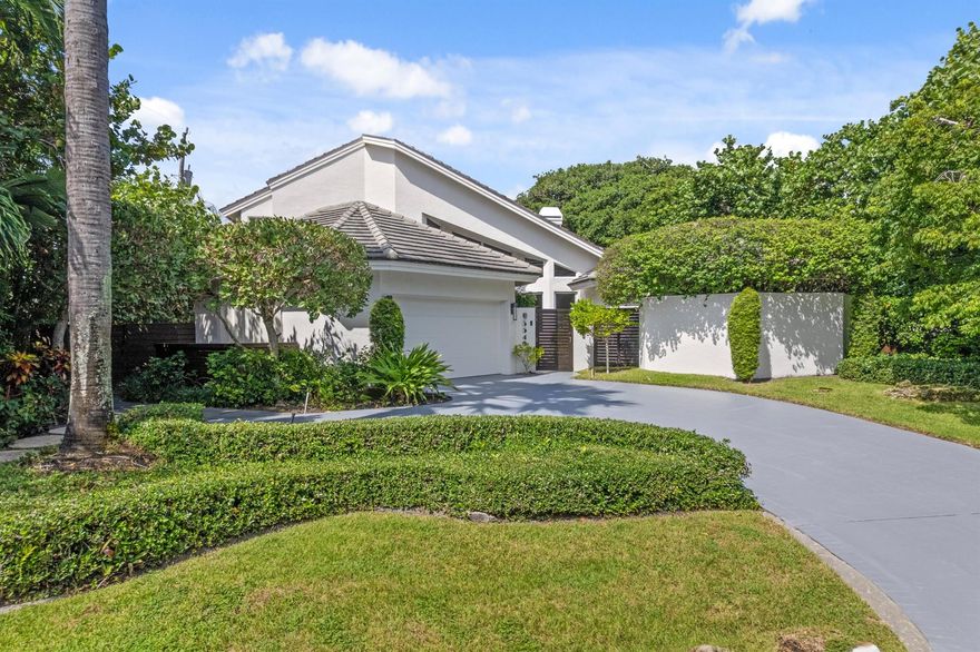 Exuding coastal sophistication, this lushly landscaped four-bedroom estate in prestigious Ocean Ridge combines modern elegance with timeless design. Dramatic vaulted ceilings, polished Saturnia floors, and a striking stone-mantel fireplace highlight the open living spaces, while walls of glass invite natural light and garden views. The expansive yard, surrounded by tropical landscaping with recent upgrades, creates a private oasis. Just three blocks from the beach, this storm-secure home features hurricane-impact windows and a generator, epitomizing refined coastal living.