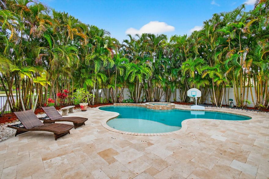 Welcome to this PICTURESQUE TROPICAL BACKYARD RETREAT overlooking tranquil lake views, designed to feel like a private resort. Set on a cul-de-sac in Olympia, this exceptional residence is highlighted by a freeform PebbleTec salt-system pool and spa, expansive travertine decking, lush tropical landscaping, and winding rock pathways that create a serene outdoor escape. Designed for effortless indoor-outdoor living, the home offers a covered patio with Phantom screens, an upper balcony with retractable awnings, and a generous side yard finished with turf, creating a beautiful low-maintenance green space. The backyard is fully fenced, providing a secure area for pets to roam and enjoy the peaceful surroundings. An 8' X 8' attached storage room provides convenient space for pool toys, outdoor equipment, and entertaining essentials. a buried PROPANE TANK efficiently heats the pool and spa and also offers the option for future generator capability. The expansive outdoor living areas create an ideal setting for entertaining, relaxing, and enjoying Florida's year-round sunshine.   Inside, the home showcases quality craftsmanship and contemporary design, featuring extensive moldings, inlaid mirrors, clean lines, and an abundance of natural light. Impact sliding glass doors and an etched impact glass front entry door enhance both style and security.....    The expansive kitchen is designed for both everyday living and entertaining, offering white shaker cabinetry, a massive counter-height island topped with exotic granite and abundant storage, while the surrounding counters feature sleek quartz surfaces. Stainless steel appliances include a new slide-in range, microwave, and dishwasher, along with a wine refrigerator and a built-in butler's pantry.....      The main level offers a versatile fifth bedroom with a full bath, currently designed with custom built-ins and ample space for a pullout king-size sofa bed-perfect for guests, a home office, or flex space.  A magnificent staircase with Mahogany steps, glass panels and rich mahogany accents creates a striking architectural feature. Beneath the staircase is a built-in nook with a decorative metal door, ideal for additional storage or even a cozy retreat for your four-legged family member. Throughout the main living areas downstairs you will find luxury vinyl plank flooring and Hybrid Plus walnut planks in the downstairs flex room and entire upstairs, with no carpet anywhere in the home.....      Upstairs features a spacious loft and four additional bedrooms, including the primary suite with a private balcony overlooking the serene backyard and lake-perfect for morning coffee or evening cocktails. The primary retreat includes two custom walk-in closets and a beautifully designed spa-style bath featuring a soaking tub and a stunning shower with book-matched exotic granite and a seamless glass enclosure.  All closets throughout the home are custom outfitted, and the bathrooms feature cohesive cabinetry, granite countertops, and double-sink vanities, including a guest bath with dual sinks and a Jack-and-Jill bath also featuring double sinks. Contemporary lighting, designer ceiling fans, plantation shutters, and solid-core interior doors add to the home's refined finish.....    Additional highlights include two new air conditioning systems, a widened driveway accommodating three vehicles, landscape lighting, gutters, accordion shutters, security cameras, and a garage with extensive cabinetry and a beautifully finished floor. The home is also equipped with an electric vehicle charging station.....      Villa Olympia offers world-class amenities, including a lagoon-style pool and spa, tennis courts, pickleball, basketball, volleyball, a playground, an indoor basketball court, and a state-of-the-art fitness center plus an outdoor entertaining patio.....  HOA fees cover 24-hour gated security, recreation amenities, common area maintenance, internet, & irrigation. Walk to A-rated schools, the Wellington Green Mall, fine dining, Trader Joe's, & Whole Foods. Close to world-class equestrian events, the Wellington Tennis Center, Palm Beach Island, and more.....      Meticulously maintained and move-in ready, this exceptional home offers a rare combination of thoughtful upgrades, beautiful design, and a picturesque lakefront setting.