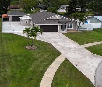 This one-of-a-kind waterfront home offers approx. 4,500 total sq ft on an oversized corner lot -- with extended driveway perfect for RVs, boats, or up to 15 cars! No HOA! Inside, enjoy spacious living and family rooms, a chef's kitchen with 10' island, custom cabinetry, and quartz countertops. The great room features a 6-person jacuzzi -- ideal for entertaining with views of the $150K custom backyard, pool, and canal. Safe & Security Cameras. It also features a 2-car front garage and an extra 230 sq ft utility garage for toys or equipment. But the show-stopper is the additional 800 sq ft Harley-Davidson-themed man cave garage with central A/C, built-in motorcycle lifts, stainless countertop, and custom tool cabinets, all valued at $225k.