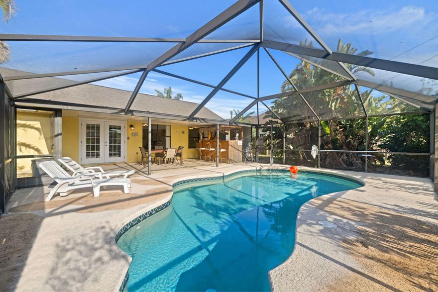 Completely renovated in 2022, this beautifully updated home offers peaceful lake views from the breakfast area and a seamless blend of comfort and style throughout. Porcelain tile flooring flows into a screened, heated saltwater pool surrounded by lush tropical landscaping, creating the perfect setting for relaxing or entertaining. Enjoy evenings at the authentic tiki bar or cook with ease in the gourmet kitchen featuring granite countertops and soft-close cabinetry. The main bathroom is designed for comfort, featuring a dual-sink vanity, individual granite countertops, and warm white pine wood accents. Showers are finished with elegant Turkish marble, complemented by porcelain soaking tubs for a spa-like feel. A fully fenced backyard with a 6-foot privacy fence.
