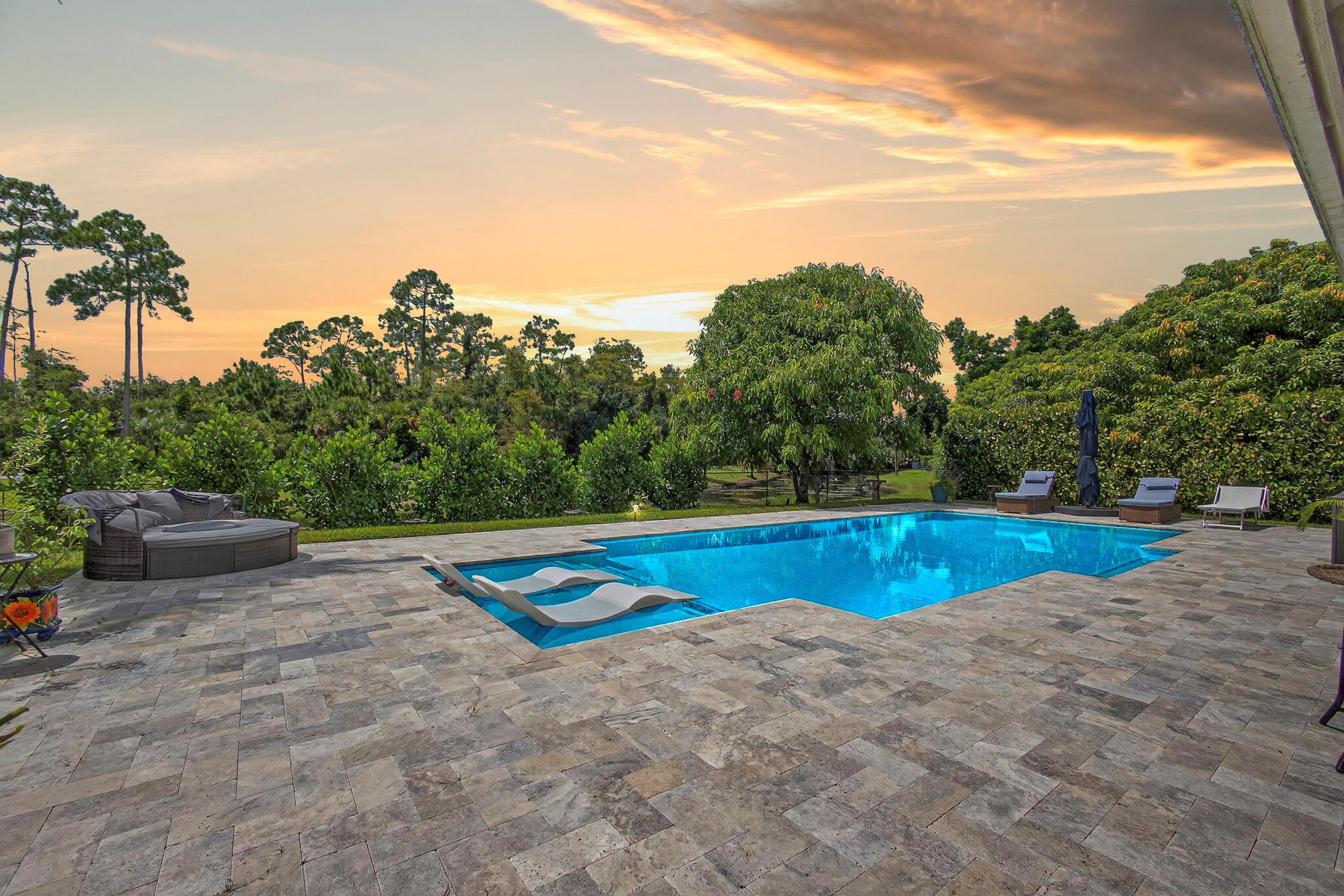 THE EPITOME OF SOUTH FLORIDA LIVING! Welcome to your very own lakefront tropical oasis nestled in the heart of Royal Palm Beach offering a lifestyle of convenience and privacy. Enjoy your morning coffee or evening cocktail soaking in our magnificent sunsets while admiring your newer salt chlorinated pool featuring a sun shelf, LED lights and a gorgeous upgraded oversized travertine pool deck surrounded by fenced-in tropical foliage and palm trees. This open and bright floor plan features 10' ceilings, a newly renovated kitchen with shaker cabinets, barn door pantry access, SS appliances, complete with a coffee bar that offers fantastic views of the incredible backyard pool area. Come and see this rare opportunity before it's too late!