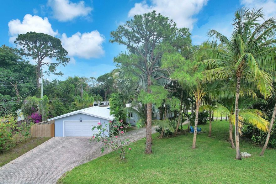 Huge, Private Corner Property Sitting on 3 LOTS with almost a 1/2-acre! No HOA! 3-Bedroom, 2-Bathroom Home with Hurricane Impact Windows and Vaulted Ceilings Throughout. 12x21 Enclosed Florida Room with New Mini-Split AC adds Extra Living Space. Updated Kitchen with OVERSIZED Stainless-Steel Island Open to the Living & Dining Room. Large Master Suite with Walk-in Closet and Stone-tiled Shower. Full-Sized Washer/Dryer Inside. Home and Garage have Metal Roof. Fenced-in Yard with Tropical Landscaping, Covered Patio and Plenty of Room for a Pool. 24x24 Detached Garage with Central Air and Space for a Bathroom. Brick-Pavered Circular Driveway with Parking for 15+ Cars! An Additional Long Driveway on the East Side of Property for Commercial Vehicles or RV/Boat. No Restrictions Here! Must See!