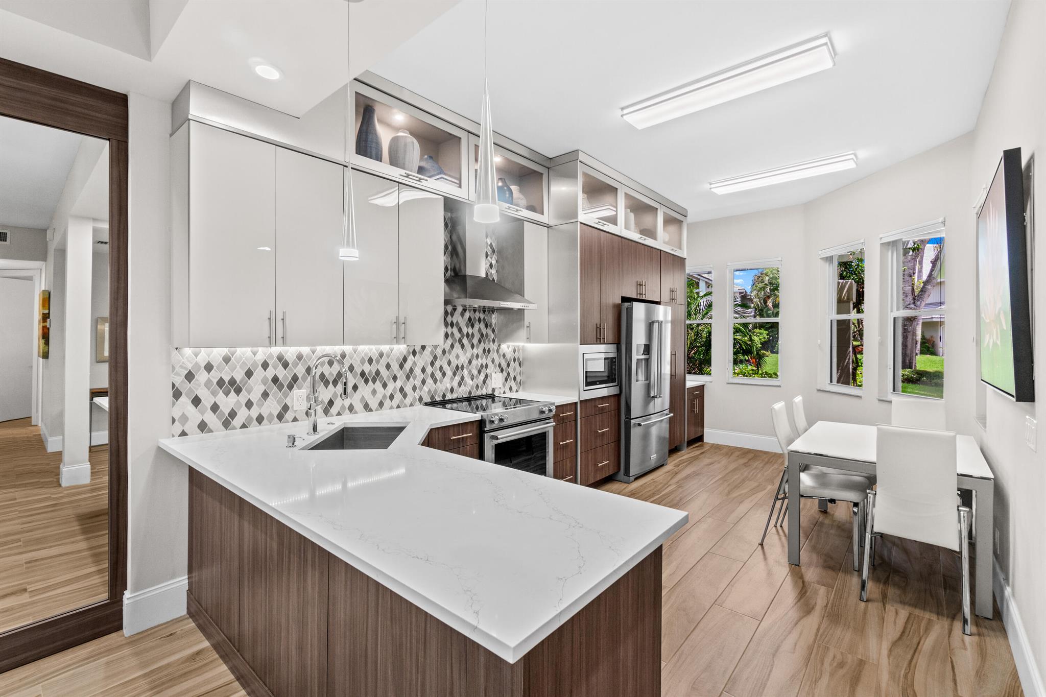 Step into this beautifully renovated, first-floor condo, where sunlight fills the interior through oversized glass-doors that frame picturesque golf course views. Every detail of this home has been thoughtfully updated showcasing modern style and chic design.The kitchen is a contemporary masterpiece completely remodeled with sleek countertops, custom cabinetry offering generous storage, stainless steel appliances, under-cabinet lighting, and a stylish backsplash. Whether enjoying a casual breakfast in the charming eat-in nook or hosting guests in the elegant formal dining area, this space is designed to impress. The open-concept living room offers a bright and airy atmosphere. Effortlessly connected to the screened-in patio, the layout offers the perfect setting for entertaining or simply