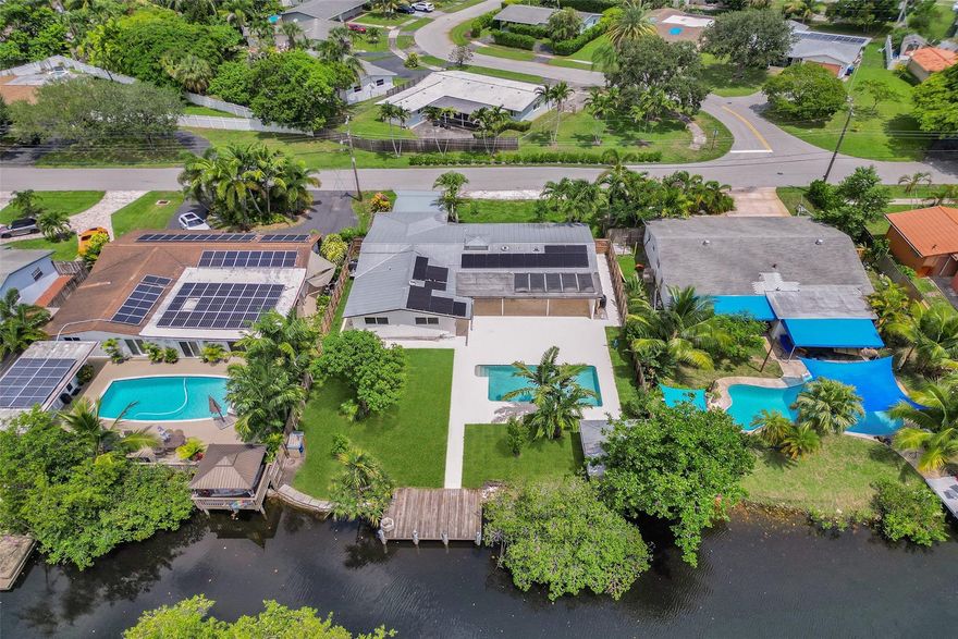 For those seeking a luxuriously remodeled, contemporary home w/ ocean access & extensive upgrades, look no further—this is your private paradise! Striking stacked-stone façade w/ 2002 metal roof & energy-efficient 2024 solar panels. Inside, the open-concept kitchen showcases shaker cabinetry, quartz counters, waterfall-edge bar & premium appliances accented in gold. Split BR layout ensures privacy, while spa-inspired baths create a resort-like atmosphere. Elegant porcelain tile flows thru/out, supported by a 2-zone AC system (2020/2022). Step outside to your oversized backyard designed for entertaining, featuring Jerusalem stone patio, sparkling pool, tiki hut & private dock. 2-car garage, sep. laundry, upgraded lighting, fans & more add to this exceptional property...a true must-see!