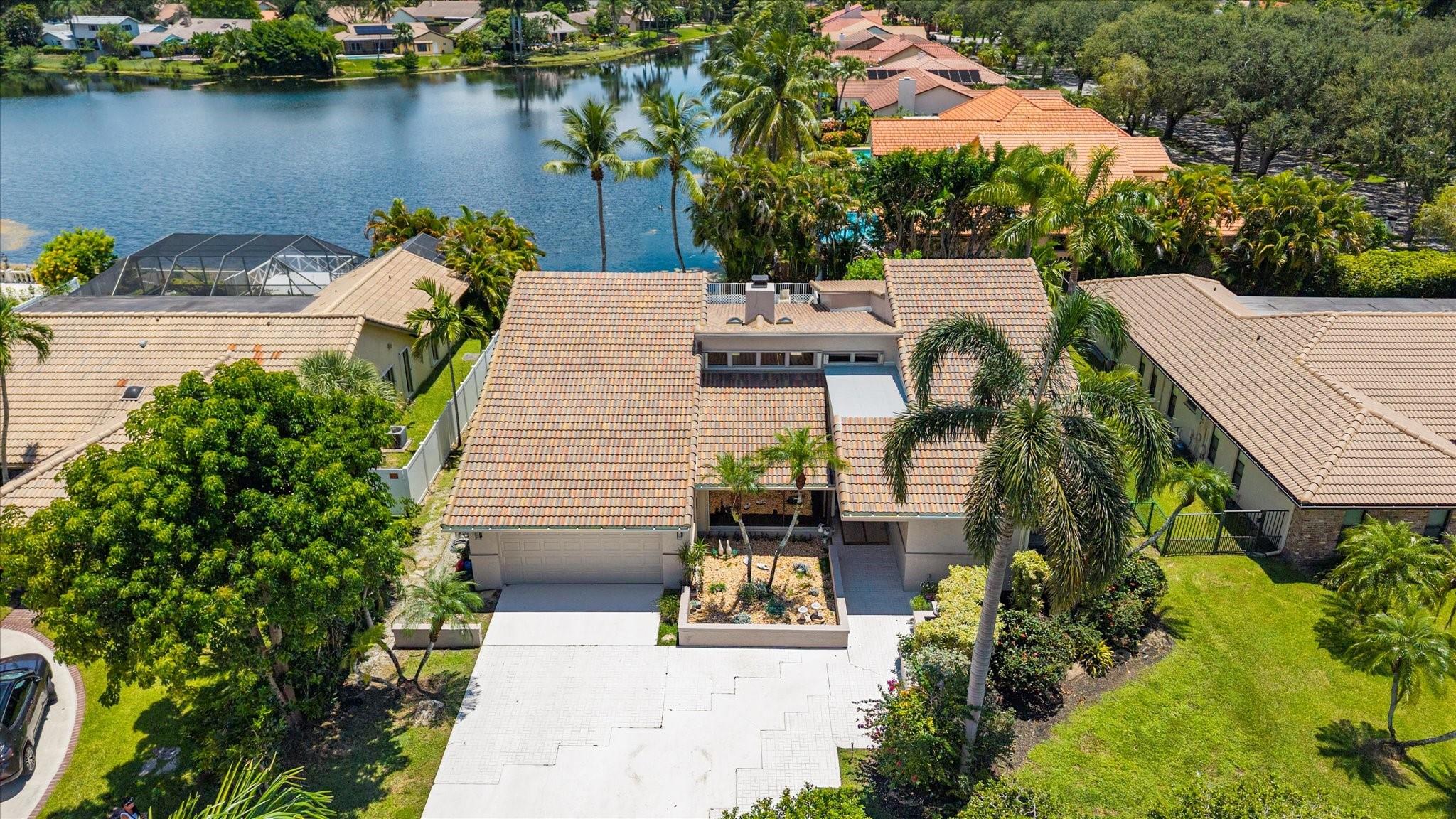 JUST LISTED! Your Lakefront Oasis Awaits in Jacaranda Lakes! This spacious 4 bed, 3 bath pool home offers 2,593 sq ft under air and peaceful lake views from your private backyard. Soaring vaulted ceilings, skylights, and a striking coral rock two-way fireplace create an open living space connecting living area, family room, and kitchen. The formal dining room features clerestory windows. Bedrooms boast high volume ceilings enhancing the spacious feel. The eat-in kitchen includes an island and double oven. Step outside to a large, covered patio with built-in gas grill. Enjoy a 2-zone A/C system, accordion shutters & impact garage door. A converted garage adds an A/C-cooled flex room plus parking for one car as-is. Barrel tile roof replaced in 2021. This is the one you’ve been waiting for!