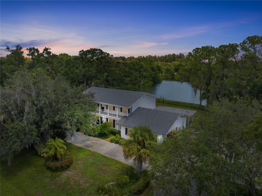 Welcome to this two-story, 4-bedroom lakefront retreat that blends comfort, style, and endless possibilities. On an oversized .62-acre lot, the home offers a spacious floor plan with formal living and family rooms, ideal for entertaining or relaxing. Recent upgrades include a new roof (2021) and impact glass windows. The two-car garage is complemented by circular and side driveways, offering plentiful parking. Step outside to your private oasis: a covered porch overlooking a fenced backyard with sweeping lake views—perfect for gatherings or enjoying the Florida sunshine. Upstairs, the balcony is the ideal spot to unwind and take in sunsets. Pets will love the unique AC dog kennel. Lakefront sunsets, privacy, and space to create your dream retreat—all right here.