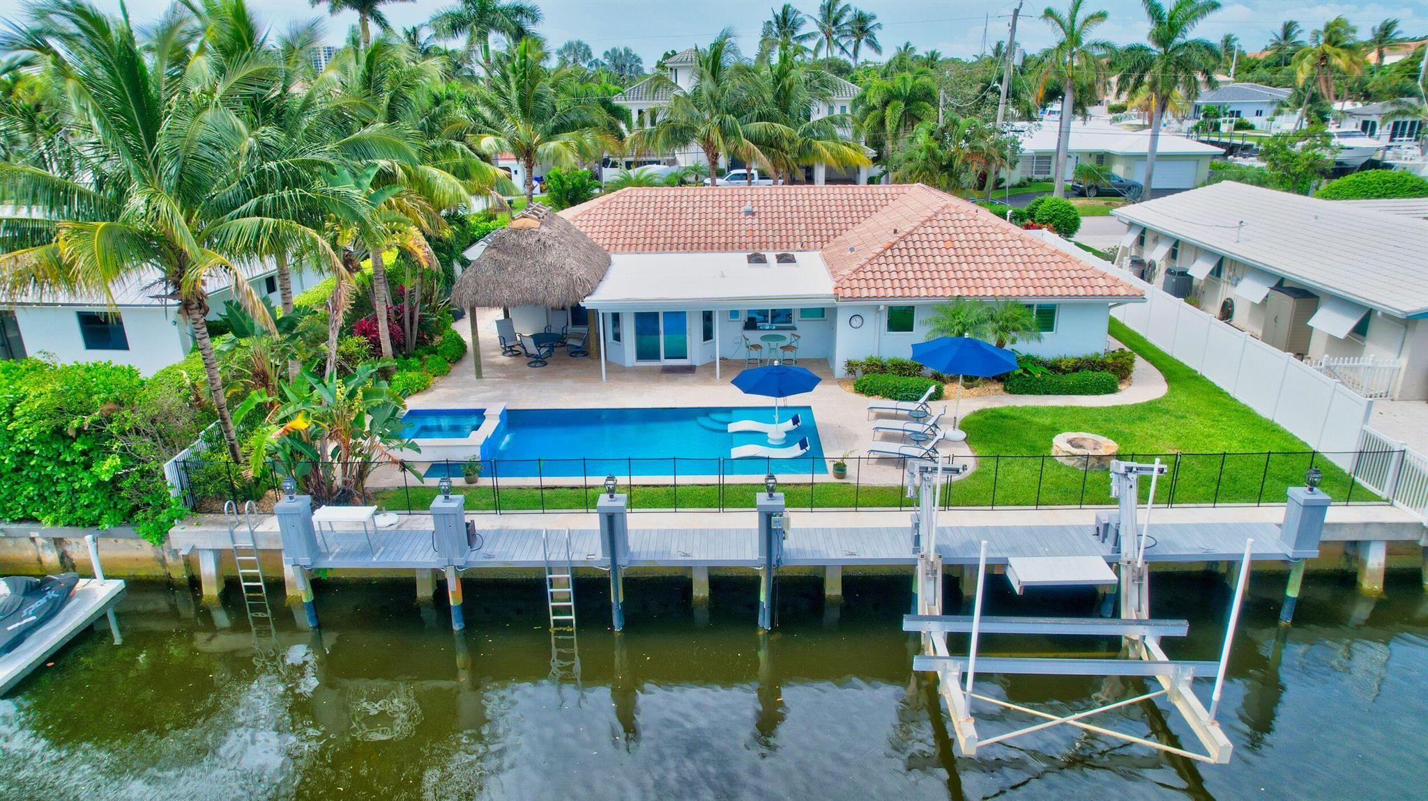 PRICE IMPROVEMENT on this stunning, east Boca Raton, waterfront home with 83 ft of water frontage, no fixed bridges and ocean access. It has been beautifully updated with wide plank tile flooring throughout, bright and open kitchen with a passthrough bar to outside.The appliances are all top-of-the-line Kitchen Aid ,Wine refrigerator, farmers sink and Quartz counters. There are also two kitchen skylights that bring the outside in. 3-bedroom Split floor plan PLUS a separate office/ den. Open formal living room, dining / eat in area. Vacation every day in the heated pool and spa, Tiki hut w/ TV dock, deck. The pool was built 2017 and has LED pool light automation. Both pool and dock have child safety fence. and over 2,000 sf of Ivory Travertine patio decking.
