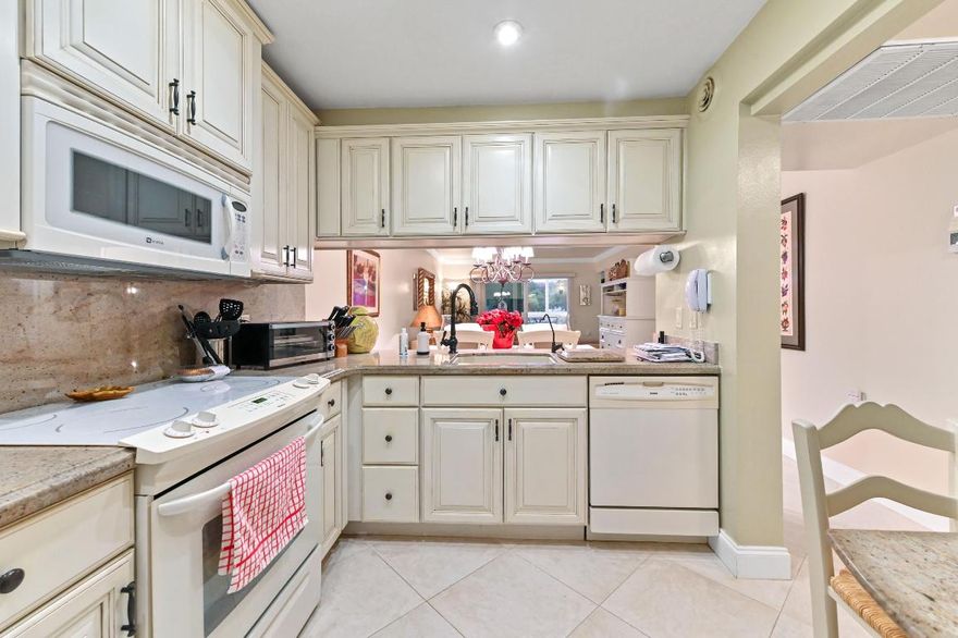 Experience spacious living in this beautiful 55+ condo, where a thoughtful layout offers far more than the standard condo experience. Beyond the welcoming foyer and pristine diagonal tile flooring, you'll discover a stunning kitchen featuring antique-white raised panel cabinetry, granite countertops, and a pass-through breakfast bar that connects effortlessly to the formal dining area. Unique to this unit is the abundance of living space; in addition to the expansive main living room with its elegant crown molding, there is a separate, cozy family room or den—perfect for a media center or home office—bathed in natural light from large windows. Retreat to the comfortable private quarters, including a serene primary suite that features ample closet space behind classic louvered doors and an ensuite bathroom. Step through the floor-to-ceiling sliding glass doors in the living room to your private screened balcony, where you can unwind while overlooking tranquil waterfront views and lush green grounds. Situated in a well-maintained building with easy access to parking and just moments from Coconut Creek's best shopping and dining, this move-in-ready home offers the perfect blend of luxury, comfort, and convenience.