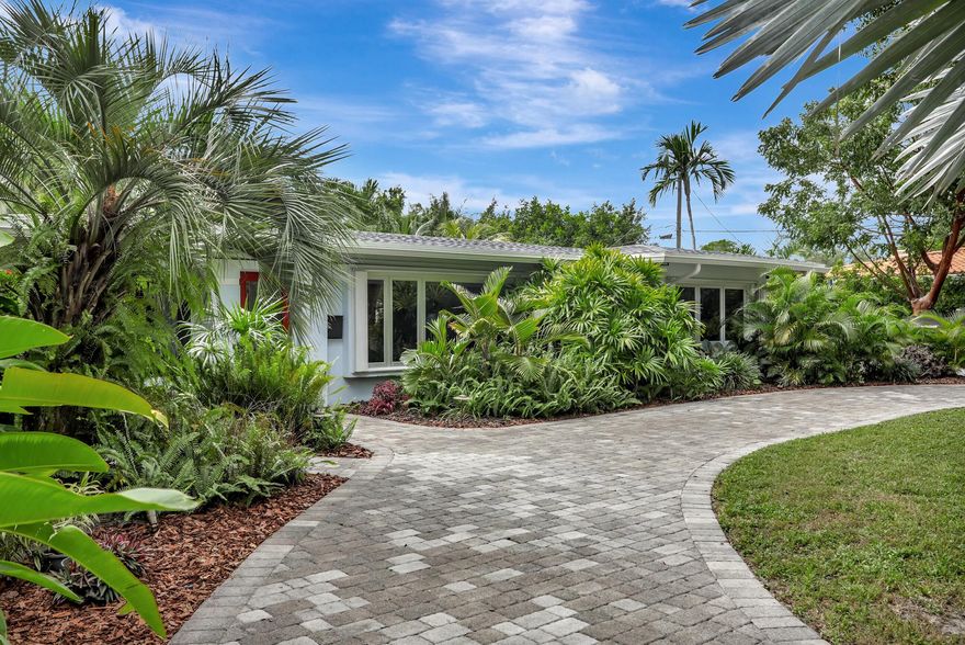 Step into your private oasis with this rarely available, exquisite 4 bed plus den, 4 bath residence, nestled on an expansive 21,000 sq ft lot (the second largest in Coral Ridge). This home has been beautifully designed and renovated, and original features restored, to create a perfect blend of style, comfort, convenience, privacy, communal and personal space. There's an abundance of natural light and lush tropical outdoor spaces to relax, rejuvenate and socialize. Large windows create an airy feel and offer breathtaking views of the meticulously landscaped garden with its inviting and completely private pool area. As you enter, a striking gas fireplace clad in pristine cloud-white Brazilian calcite in the living room sets a welcoming tone, blending with the beautifully restore