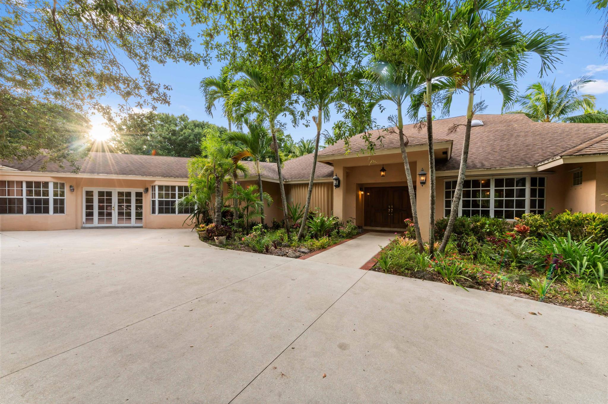 Experience the rare opportunity to own a one-of-a-kind estate in Palm Beach Farms--one of only two designated rural overlay areas in Palm Beach County. Situated in unincorporated Palm Beach County with no HOA, this property offers privacy, space, and flexibility for collectors, home-based businesses, and multigenerational living. Located just minutes from Palm Beach International Airport, the Turnpike, I-95, shopping, schools, and Wellington Mall, yet tucked away in a tranquil setting with limited road access, this hidden gem offers country charm within urban reach.The property features a custom-built $700,000+ multi-tiered waterfall with 15+ drops, natural boulders, beach entry pond, and a fully powered dock gazebo.