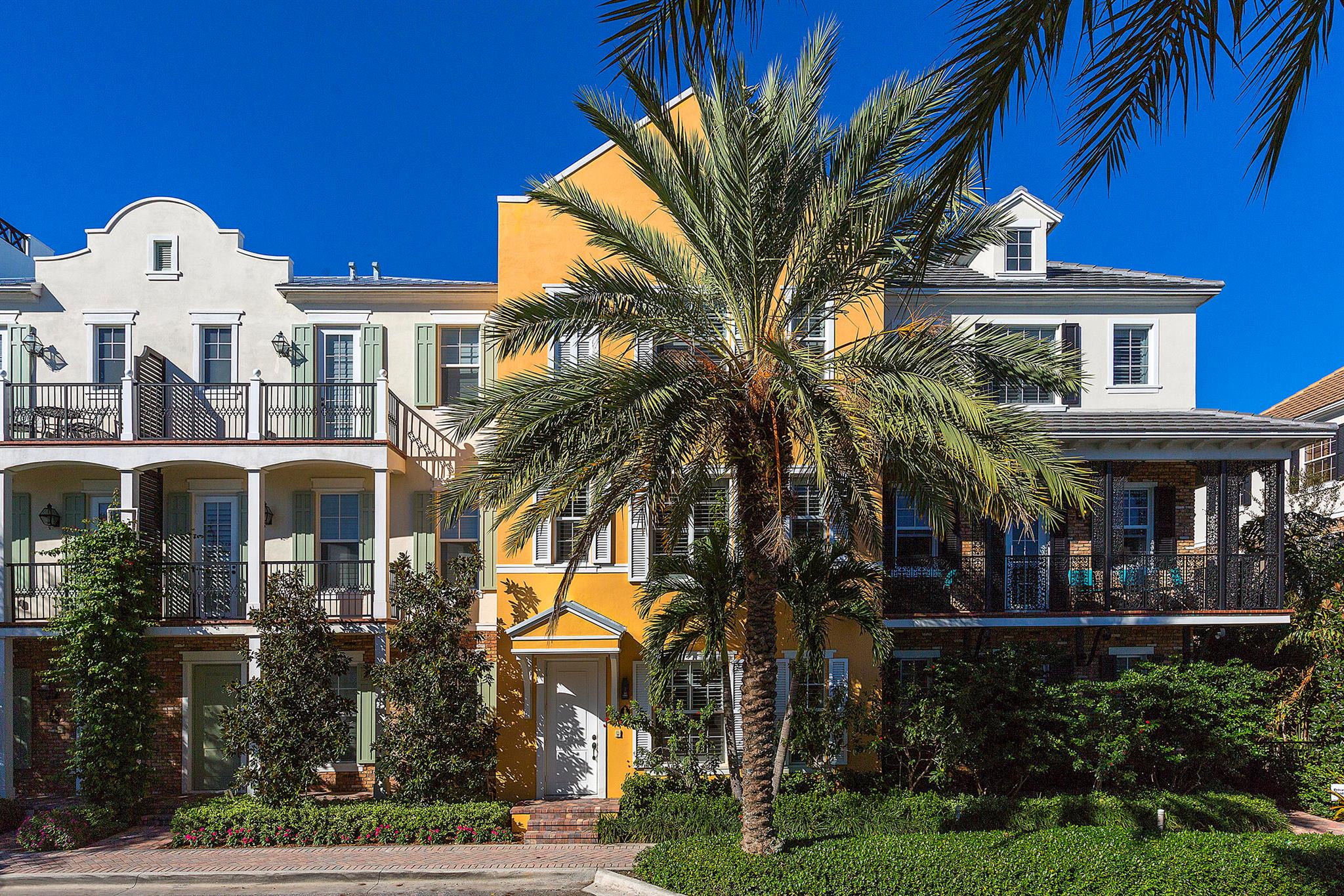 Located in the heart of Pineapple Grove Village, this beautifully upgraded townhouse in Cannery Row offers refined living in one of downtown Delray Beach's most desirable communities. The first floor includes a spacious two-car garage and a private en-suite bedroom with a bathtub ideal for guests or as a quiet home office, separated from the main living areas. A staircase with solid hardwood treads and risers leads to the second floor, where you'll find matching wood floors and a thoughtfully designed layout. The large eat-in kitchen features white Shaker-style cabinetry, light granite countertops, and an oversized island that functions as both a practical workspace and a central gathering spot. Opposite the powder room, a bright formal living room is framed by large windows, bright