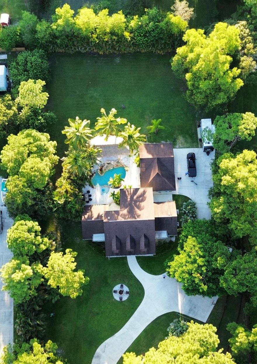 Exquisite Jupiter Farms Estate! Own a slice of tropical paradise in the prestigious Jupiter Farms community. This fully furnished 4-bedroom, 2.5-bathroom custom masterpiece redefines luxury living, blending unparalleled elegance with the laid-back allure of a private oasis. Tropical Haven: Indulge in a Margaritaville-inspired backyard with a sparkling pool, custom tiki bar, and shaded tiki hut—perfect for lavish entertaining.Spacious Elegance: Four expansive bedrooms and 2.5 spa-like bathrooms, complemented by impact windows/doors for security and sophistication.Versatile Retreat: Fully air-conditioned detached garage, ideal as a guest suite, executive office, or studio.No HOA=Freedom: Embrace unrestricted luxury in this AG/Residential enclave.RV/Boat Paradise: Pad with 30&50 amp