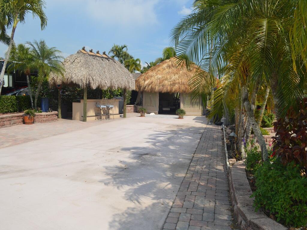 Reduced and priced right! Golf and waterfront fountain views only start to describe this large lot with two tikis! Smooth blend of cement and pavers in all the right places! The larger tiki allows room for entertaining or spacious relaxing was just rethatched! Isinglass shades keep the elements out for everyday use! Nice extended area behind tiki to soak in the sun. Most furnishings, TV and firepit are included for move in ready fun! Kitchen/bar tiki is well equipped with fridge, storage and cooktop and a second TV! Tons of storage units to remain, tranquil fountain, mosquito control are in place. Plenty of room for a 45' bus, vehicle and golfcart. Located in the gated community of the Motorcoach Resort Saint Lucie West. Class A only coaches.