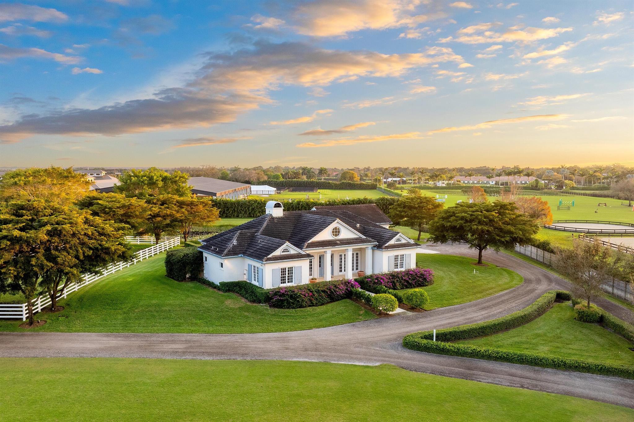 Discover this exquisitely designed estate, featuring a private 28-stall barn, a lush Grand Prix grass field, a covered arena, an outdoor ring, a Euro-walker, and a round pen, all nestled on 8.85 acres of beautifully manicured land. Perfectly located just minutes from WEF, Global, and IPC competition venues, this property is a dream for equestrian enthusiasts. The barn is thoughtfully designed with two mirror-image wings, each offering 8 wash stalls, 2 tack rooms, 2 feed rooms, 2 laundry rooms, 2 kitchens, 2 bathrooms, and 2 storage rooms. The elegant 4-bedroom residence includes an office and features an open-concept great room with a center-island kitchen, a professional gas range, quartz countertops, a stunning glass-enclosed wine cellar, and beautiful wood floors throughout.
