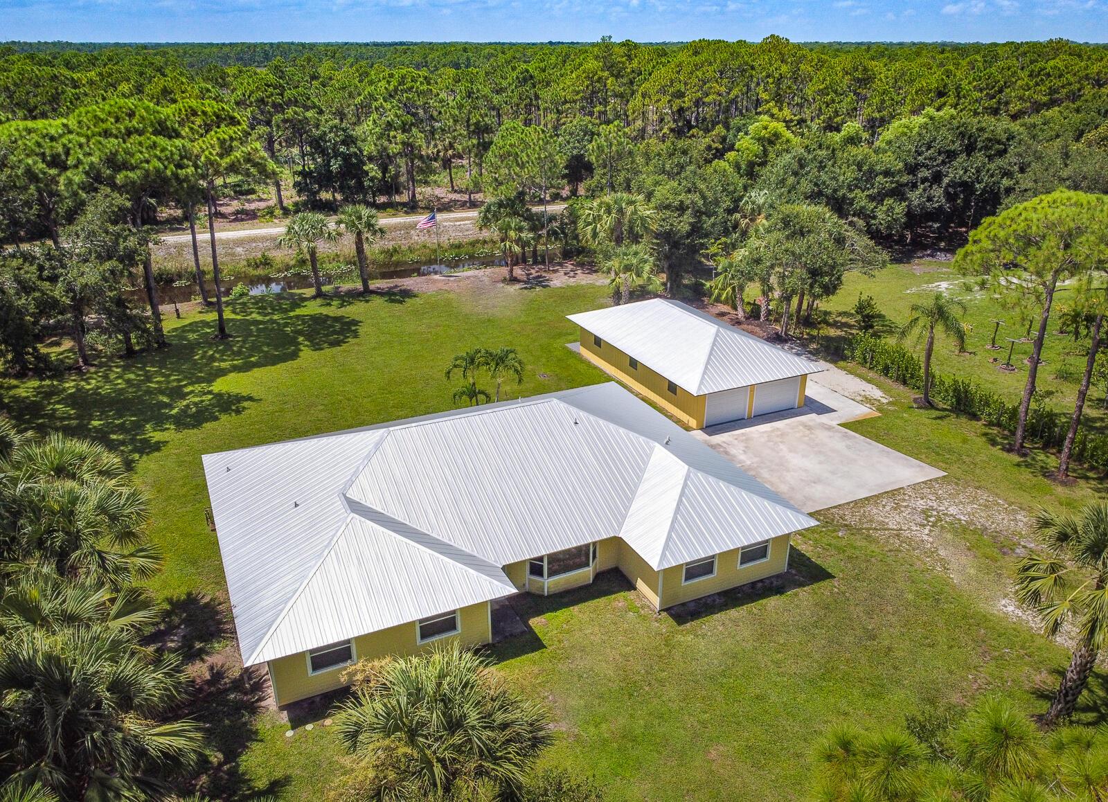 This 4BR/3BA home with a detached 24'x45' garage is the perfect project home - situated on one of the nicest properties in Palm Beach Country Estates: a RARE 1.34-acre lot on a paved road that backs up to a canal and 10,000-acre nature preserve. The interior has been partially gutted down to the studs - ready for new drywall, kitchen, electrical, flooring, etc. Many improvements already installed: NEW metal roof on both house and garage in 2023; NEW 26kW Generac whole-house generator with 1,000 gallon buried propane tank stubbed out for additional future hookups; NEW PGT hurricane impact sliders and cabana door. Two of the three bathrooms are newly-updated.