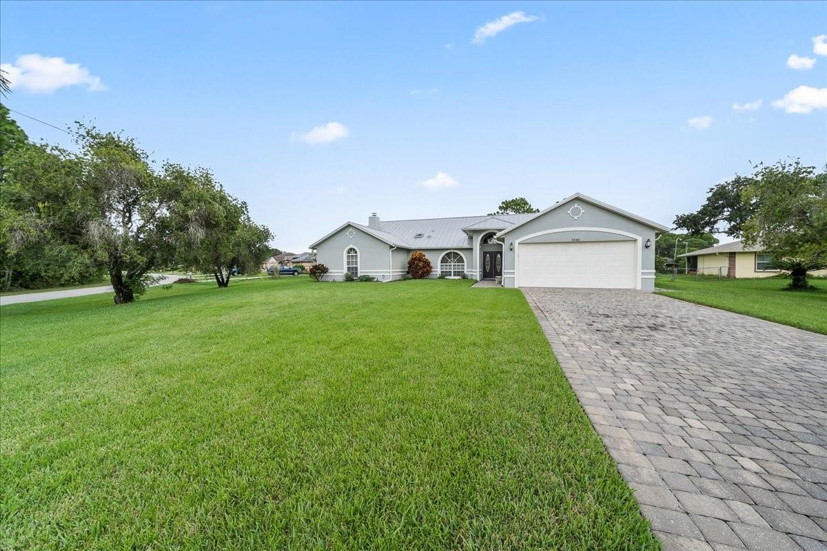 Welcome to this stunning 3-bedroom, 2-bathroom home nestled on a spacious .44-acre lot in the quiet, sought-after neighborhood of Palm Bay. This home boasts modern upgrades and thoughtful touches throughout. Key Features include a durable steel roof, complete with new gutters and Leaf Filter gutter covers. The lifetime warranty on the gutter covers is fully transferable to the new owner. At the end of the driveway, a newly installed culvert efficiently manages rainwater and prevents flooding. Freshly painted inside and out, giving this home a clean and inviting feel. Enjoy outdoor living on the large back porch, featuring beautiful sealed pavers,perfect for relaxing or entertaining. New flooring has been installed throughout, with carpet in only two bedrooms for added comfort. A must see.