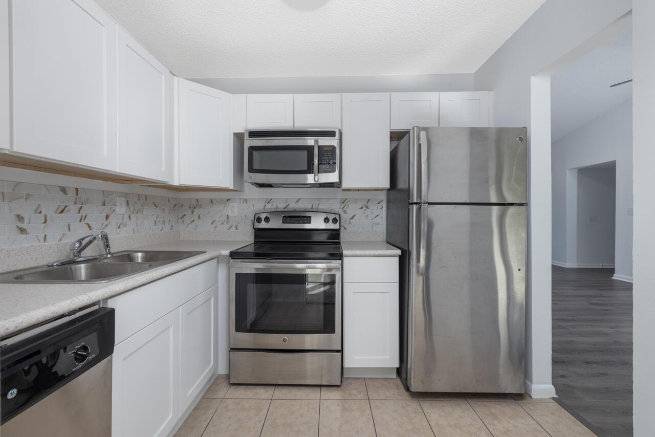 Welcome to your captivating 2 bedroom, 2-bath, second-floor condo that features a NEW 2021 METAL ROOF and offers the perfect blend of comfort and coastal living. Step inside to discover 13-ft vaulted ceilings and an enclosed Florida room, providing extra living space to take in picturesque views of lush native trees along with an abundance of natural light. The interior exudes beachside cottage charm, with luxury vinyl plank flooring, stainless steel appliances, updated countertops and fresh paint. Located in Dolphin Village, along Warner Creek, all-age community, residents enjoy access to fantastic amenities, including a marina, two pools, a tennis/pickleball court, a billiard room, a sauna, indoor showers, and two clubhouses. Just a short 10-minute drive to the beach, this turnkey