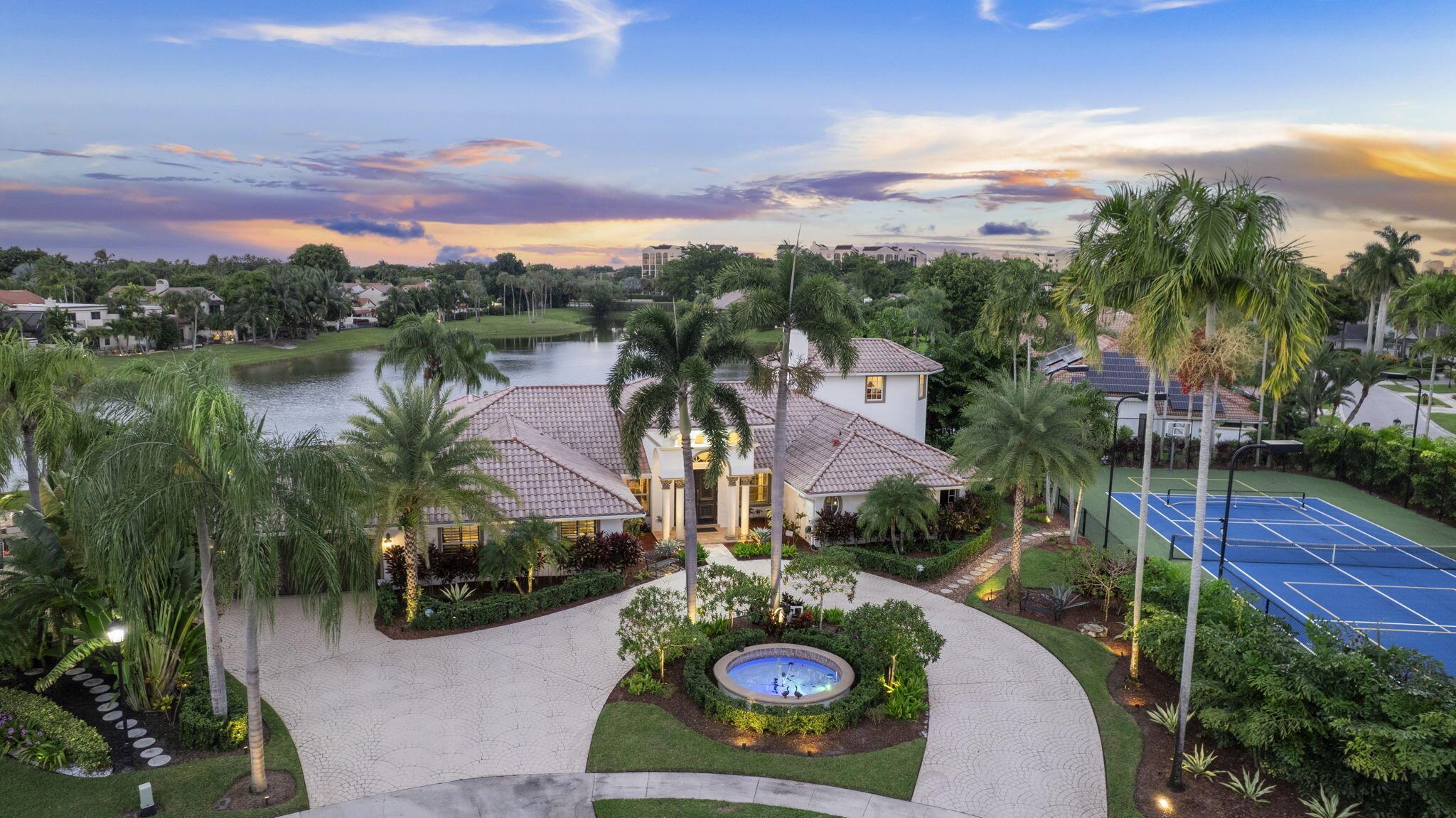 Rare Double-Lot Boca Raton Estate with Private Pickleball/Tennis Court. Every detail of this residence has been thoughtfully designed, blending luxury, comfort, and functionality. From the moment you arrive, the expansive circular driveway and impressive front entry make a grand first impression. Step through the massive solid wood front door and into a stunning living room complete with a decorative wood-burning fireplace and long lake views that create a serene backdrop. The spacious primary suite is a true retreat, featuring a private sitting area, direct access to a second-floor office via a rotunda staircase, two custom walk-in closets, and a luxurious bathroom with a jet tub, separate shower, and dual vanities.