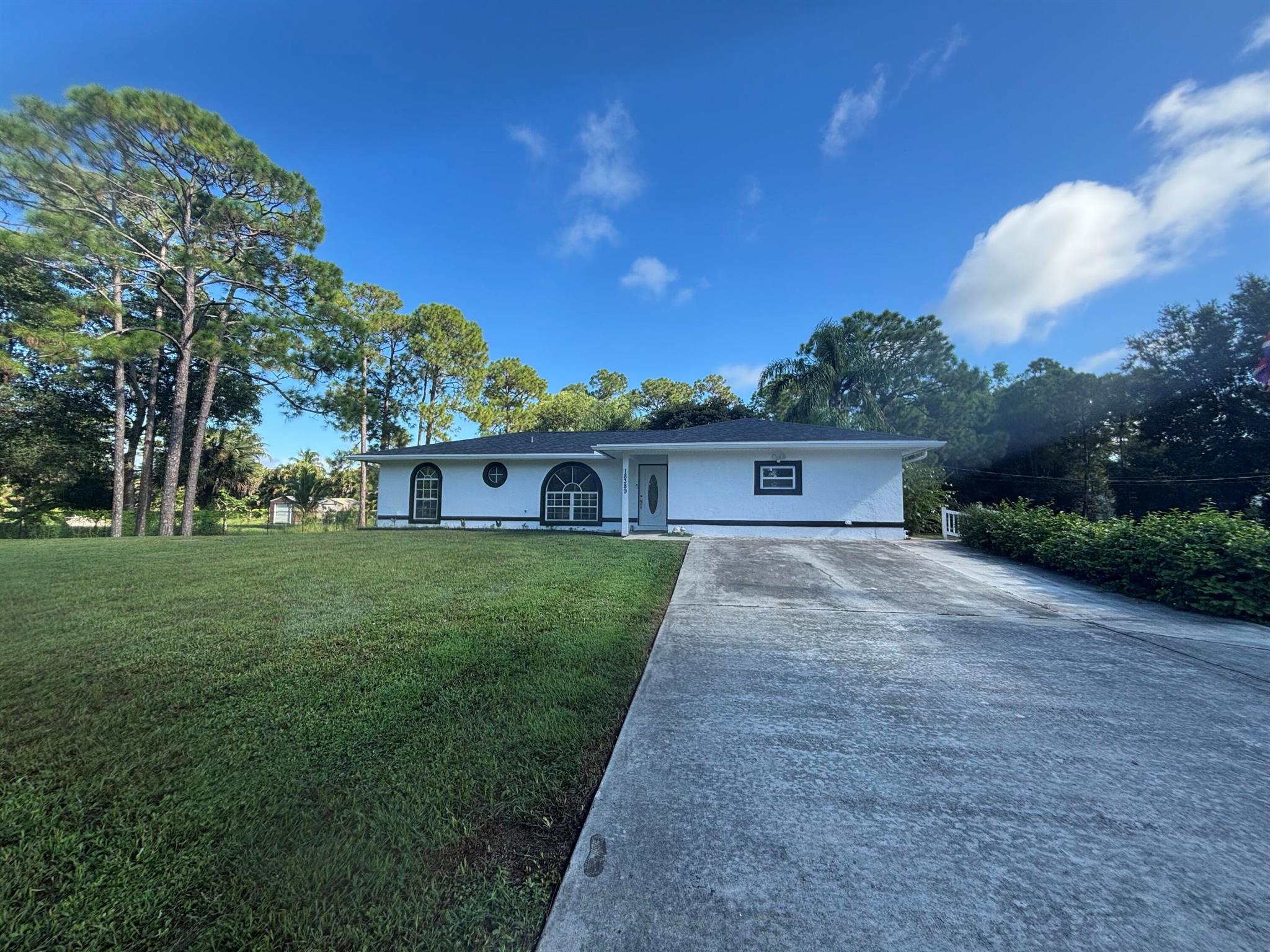 Professional pictures coming soon!!! Move in ready 3 bedroom, 2 bathroom home on 1.15 acres in The Acreage! Completely remodeled in the last year with nearly everything brand new. Updates include: roof, gutters, A/C, tankless water heater, whole home water filtration (Dec 2024), fresh exterior and interior paint, new flooring, baseboards, bedroom & closet doors, ceiling fans, blinds, and outlets (2025). Both bathrooms and the kitchen were fully renovated with new finishes and appliances (2025), plus a new washer and dryer (2024). Enjoy a screened in back patio for sunsets, two attics for extra storage, and a detached shed. The property is fully fenced with two gated entrances perfect for RVs, boats, or trailers. Truly one of a kind and ready to move in!