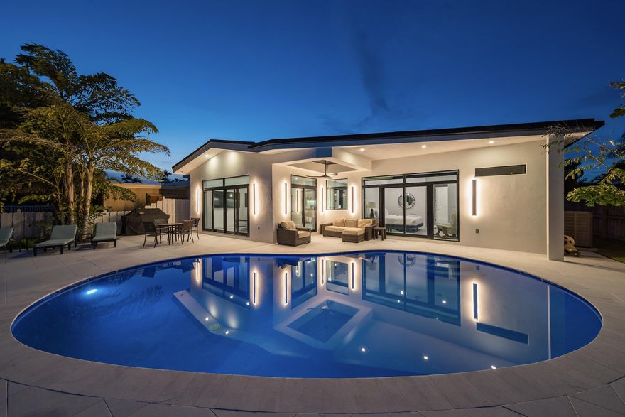 FULLY rebuilt in 2024 with soaring 10ft ceilings, this stunning 4-bedroom, 3-bathroom waterfront pool home offers 60 feet of ocean access with no fixed bridges, raised seawall with brand new composite dock, new roof, and a modern open layout designed for luxury South Florida living. From the moment you enter, the home feels bright, open, and brand new. Large impact windows and sliders, and wide-format 30x60 porcelain flooring throughout create a clean, modern aesthetic filled with natural light. The spacious layout features oversized bedrooms and a seamless flow between living, dining, and kitchen areas. The custom kitchen is designed as a true centerpiece with a waterfall quartz island, full quartz backsplash, stainless steel appliances, and a built-in beverage fridge, making it ideal for entertaining. Motorized blinds, custom closets, and high-end finishes throughout enhance comfort and functionality. Bathrooms are finished with porcelain slab walls and curbless showers, delivering a sleek, modern design. Additional interior upgrades include 8-foot solid-core interior doors, a Rheem tankless water heater, Nest thermostat, and full impact windows and doors. Step outside to a private waterfront retreat featuring a new heated saltwater pool with custom color-changing LED lighting, marble pool decking, and a covered outdoor seating area perfect for relaxing or entertaining. The property offers 60 feet of ocean access waterfront with no fixed bridges, a new raised seawall, a new composite dock, and a 15,000 lb boat lift, providing effortless access to the Intracoastal and ocean.  This move-in-ready waterfront home combines new construction quality, modern design, and direct ocean access, making it ideal as a primary residence, second home, or boating-focused luxury property.  Pompano Beach is one of South Florida's fastest-growing coastal communities, offering an elevated blend of Waterfront lifestyle, convenience, and long-term investment appeal. The revitalized beachfront offers world-class restaurants and luxury destinations, including The W, Ritz-Carlton, and Waldorf Astoria. Enjoy the Pompano Beach lifestyle with an abundance of rooftop lounges, casual oceanfront dining, the iconic fishing pier, and new waterfront parks designed for an active, outdoor lifestyle. Downtown continues to evolve with the completion of the new City Hall and expanded civic spaces, while walkable neighborhoods and the Circuit electric rideshare make getting around easy and efficient. With quick access to intracoastal waterways and ocean access just minutes away, Pompano Beach is a boater's dream community. Local pickleball courts, neighborhood parks, and multiple championship golf courses throughout the area are the cherry on top. For travelers and commuters, you'll have easy access to US-1 and I-95. FLL Int'l Airport is 20 minutes away, Miami Int'l Airport is 45 minutes away, and Palm Beach International Airport is 40 minutes away.