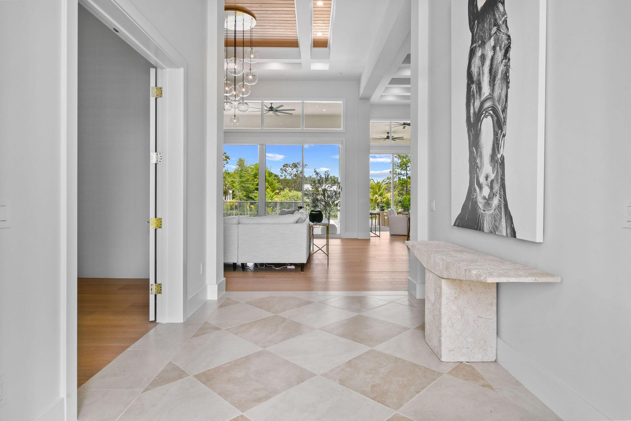This brand-new, designer-furnished home is ready for immediate enjoyment in one of Jupiter Farms' most desirable locations. Nestled on 1.25 acres along a fully paved street, this property blends luxury living with a serene, natural setting--just minutes from I-95 and steps from Riverbend Park's scenic trails and kayaking.Inside, you'll find soaring 16-foot ceilings, an open-concept floor plan, and premium finishes throughout. The chef's kitchen features GE Monogram appliances, perfect for cooking or entertaining in style. An oversized 1,200+ sq ft attached garage provides plenty of room for storage, hobbies, or equipment.The outdoor living area is equally impressive, featuring a heated pool surrounded by elegant marble pavers, a fully equipped outdoor kitchen,
