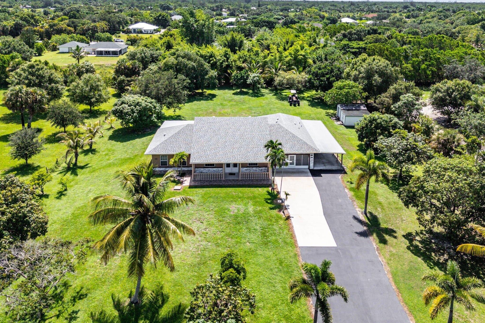 Immaculate and spacious 4-bedroom, 2-bath, 2-car garage home on over 1.5 acres on paved road access in Jupiter Farms! This well-designed property offers a split floor plan featuring a formal dining room, kitchen with granite counters opens to large family room and casual dining area. The entire home is tiled with a decorative tile inlay at the front door. Retreat to the oversized master suite with an extra-large walk-in closet and generous master bathroom. Additional expansive 49' x 18' enclosed patio--ideal as a game room, gym, or entertainment space, complete with a wet bar. The 2 car garage has been converted into a second kitchen and dining area, perfect for in-law living or extended family use. A one car covered parking area located just off the garage. For your security there ...