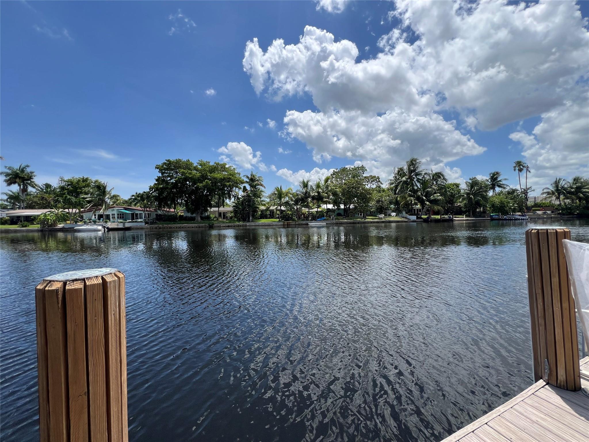 Beautifully situated at the water's edge overlooking the wide Middle River, this 2-bedroom townhome offers quiet living yet within an easy 5-minute walk to Wilton Drive. Expansive glass throughout brings in abundant sunshine to this home which features a striking Italian kitchen with gas cooktop and high-end appliances, porcelain and bamboo floors, spacious bedrooms with impressive storage. Countless entertaining options with a private front courtyard, an outdoor kitchen with both a patio and even a dock for your boat. Other highlights include the carport with secure storage, a separate storage shed and pull downstairs for attic access. The association offers a heated pool, clubhouse, dog park and a guest parking lot. Impact glass, new Rheem AC and new roof 2021, new electrical panel.
