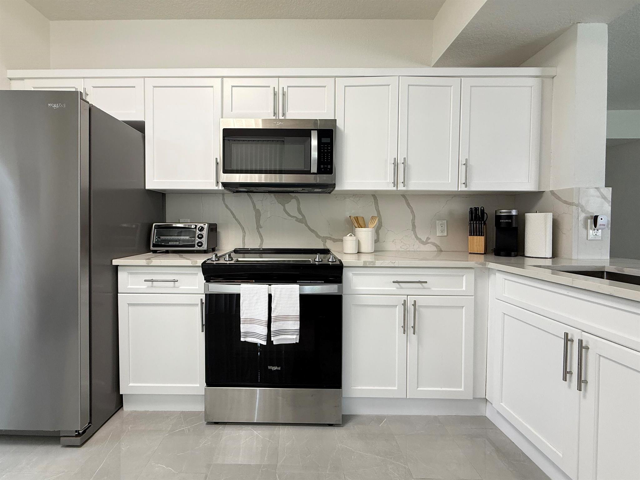 Rare opportunity! The only condo currently available at Legacy Place with a private attached garage and direct entry into the unit-no hallways or breezeways! Beautifully updated 1 bed / 1 bath first-floor corner unit featuring an open floor plan, quartz kitchen countertops, custom white shaker cabinetry, stainless steel appliances, gorgeous tile flooring throughout, oversized shower, full-size washer/dryer, and a covered private patio. The whole unit was freshly painted and equipped with custom modern lighting. This is a gated, pet-friendly community offering resort-style amenities: pool, spa, fitness & business centers, tennis, grilling areas, and more. Walk to shops and restaurants. Minutes to beaches, Gardens Mall, and PBI. Can rent immediately-perfect both for investors and homeowners