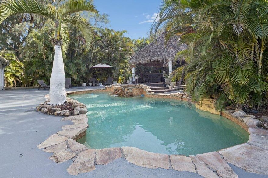 Discover ultimate comfort and entertainment in this 4-bed, 3.5-bath Davie home on 1.23 acres in Florida Fruit Lands. The main home features travertine floors, crown molding, granite kitchen with gas stove, 3-zone A/C, and two fireplaces—one in the family room, one in the upstairs primary suite with his and hers closets, double sinks, tub, and separate shower. Entertain outdoors with a swimming pool, two gazebos, half basketball court, tree house, swings, and poolside half bath. Includes a guest house with 1 bedroom, bath, kitchen, and flex room, plus a tile roof and new water filtration system. A must see!