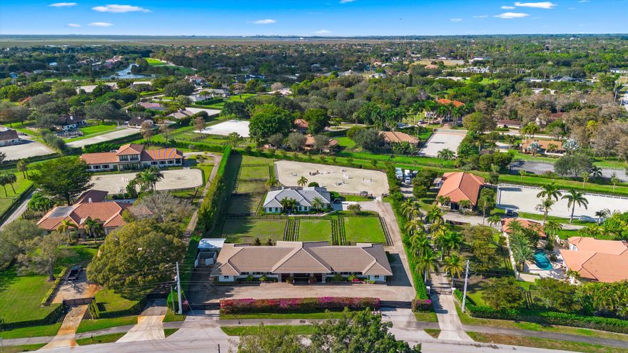 Beautifully renovated property with new roof, impact windows/doors, updated HVAC, LED lighting, 26kW generator, 4K security system, and new gates. Features a remodeled GE Café kitchen, luxury master suite, upgraded baths, saltwater pool, UV water system, new well pump, enhanced irrigation, new garage door/flooring, and water heater with booster. Two updated guest/grooms' quarters include HVAC, kitchenettes, and private baths. Equestrian amenities include a 2021 CBS barn with fly system, A/C tack/feed room with bath, four wash stalls, hay storage, an all-weather Premier ring, six paddocks.  2.15-acre property is located right on the bridle path and is a short hack to the show.