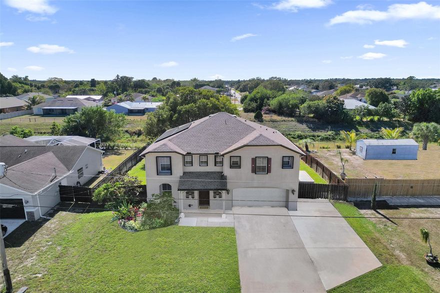 Price Improvement! Spacious 3,057 sq ft two-story home designed for comfortable family living and entertaining. MAJOR UPGRADES INCLUDE A NEW ROOF (2023), FULLY PAID SOLAR PANELS, HURRICANE PROTECTION, WIRED CAMERA SYSTEM, AND GENERATOR HOOKUP—providing efficiency, security, and peace of mind. This 4-bedroom, 3-bath layout features oversized bedrooms with walk-in closets, a versatile upstairs loft, and a main-level guest or in-law suite. The open kitchen flows to a 10x40 screened patio, overlooking a fenced yard and canal, perfect for relaxing or hosting gatherings, plus a well-water sprinkler system. Bring all your toys with an extra-large extended driveway for RV, boat, or golf cart parking, along with a two-car garage with storage, separate shed, and freshly finished garage floor.