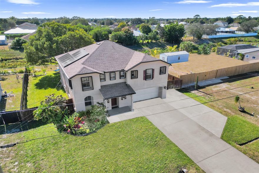 Price Improvement! Welcome home to this expansive 3,057 sq ft two-story single-family residence designed for comfortable family living and entertainment. Featuring 4 bedrooms and 3 full baths, the thoughtful layout offers oversized bedrooms with walk-in closets and a loft upstairs, plus a guest or in-law bedroom on the main level. Peace of mind comes with a new roof (2023), fully paid solar panels, hurricane protection, wired camera system, and generator hookup. The kitchen opens to a large 10x40 screened patio, fenced yard overlooking the canal, and well-water sprinkler system—perfect for all your family entertaining. Space for toys with an extra-large extended driveway for RV, boat, or golf cart parking, an two-car garage with storage, separate shed, and freshly finished garage floor.