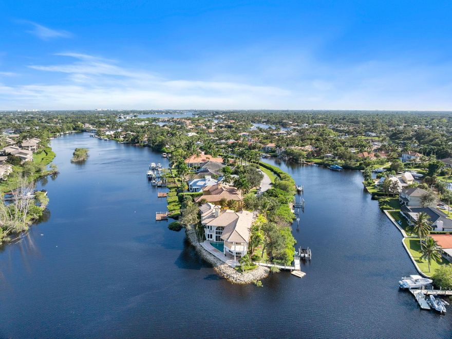 Experience the pinnacle of waterfront living in this extraordinary custom estate, gracefully positioned on a rare point lot at the tip of a private peninsula on the scenic Loxahatchee River. Set within a gated enclave w/ over 400 feet of water frontage, this home offers unmatched privacy & panoramic views of the river & surrounding nature preserve. Designed for those who value timeless architecture & the beauty of natural surroundings, the residence features soaring ceilings & expansive living spaces including 4 large bedrooms, private office w/ coffered ceilings, billiard room, workout room, sunken wet bar & a spacious gourmet kitchen.The primary suite provides a serene retreat w/ coffee bar, private waterfront balcony & sweeping river views. While this original residence (see more)...