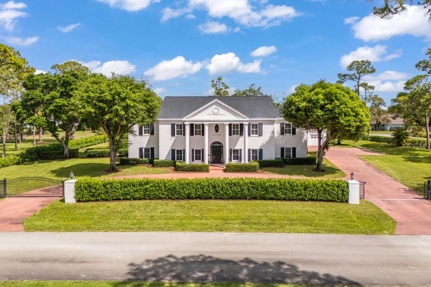 Experience the epitome of luxury in this meticulously maintained two-story colonial architecture style estate with its graceful symmetry, stately elegance and modern flair nestled on 1.24 acres.  Built in 1999 this spectacular residence features 6 bedrooms, 4.5 bathrooms, guest house, 4-car garage, workshop, resort style pool with outdoor shower, enclosed lanai, 5,137 living SF, 6,913 total SF, mature oak trees and lush clusia hedges situated on a corner prime lot in the distinguished community of Paddock Park 1 in the heart of Wellington with no HOA. As you step inside you are greeted by greatness, an elegant foyer with a gorgeous chandelier, electric sconces and plantation shutters throughout, a stylish dining room, a flex room, a spacious cultivating living room with gas fireplace.  A sophisticated primary suite with a spa-like ensuite with vanity, soft lights, dual sinks, jet tub, separate shower, toilet room, walk-in closets and a door going out to the lanai. Moving along to the second story you will find hardwood floors throughout, four spacious bedrooms, large closets, two dual-access en-suite bathrooms, a mezzanine gallery with open windows blending a curated artistic space with natural light.  As you step out onto the screened in covered lanai you will see a resort style oversized pool with outdoor shower, expansive yard for entertaining, guest house with one bedroom, one bathroom, living room, dining room, kitchen and laundry. This property is equipped with top-tier systems for comfort and peace of mind, including a full-house generator, propane tanks, impact windows, impact doors, shutters, Roof 2024, four A/C zones, clean-air UV lighting in all A/C units, four water heaters, underground propane tanks, alarm and camera system, electrical gate, dog electric fencing, lengthy paved driveway with attached  4-car garage.  This well-appointed estate delivers a sense of grandeur and sophistication, where distinctive architecture meets elevated modern living.  Professional Photos Coming Soon!