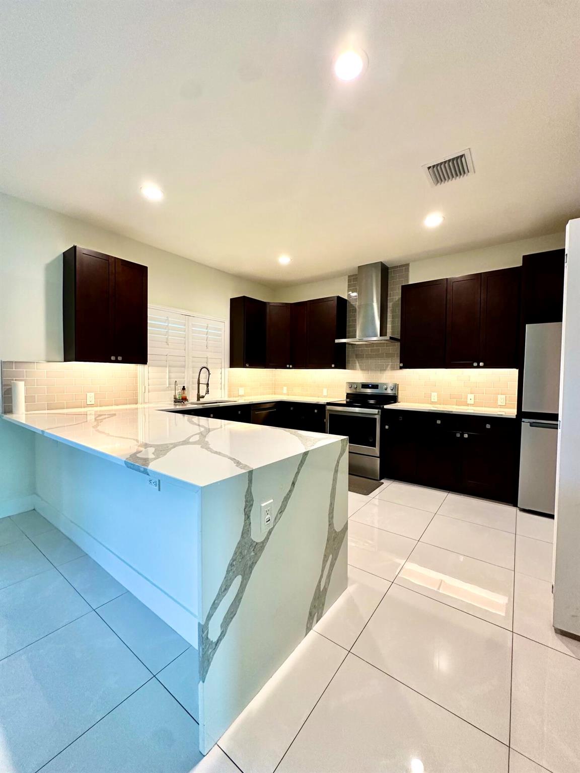 Beautifully upgraded 4BR/3BA in the Becker area, built in 2022 on an oversized lot with no HOA. This move-in ready home offers impact windows, large porcelain tile throughout, and a stunning kitchen with quartz waterfall countertops. Inside you'll find custom-built pantry and closet shelving, plantation shutters on every window with a motorized shade on the slider, and a full-house water purification system plus a separate drinking/cooking filter. The home's electrical panel is generator-ready for peace of mind. Outdoors is just as impressive with a dug well and irrigation system, lush upgraded lawn, 6-ft white privacy fence, and a tropical retreat filled with mature fruit trees--mango, guava, avocado, June plum, and bananas to name a few. Conveniently close to I-95, shopping & beaches.