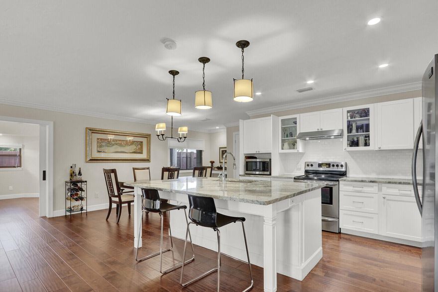 Opportunities to own a pool home on a HALF-ACRE lot in Port St. Lucie are increasingly rare, especially in the heart of coveted Sandpiper Bay! With no HOA, this property offers exceptional space, privacy, and endless possibilities for outdoor living, future enhancements, discreet storage for a boat or RV, or simply the luxury of elbow room. The beautifully renovated interior is designed for effortless living and comfortable entertaining. Natural light pours through wide French doors, illuminating the open great room and enhancing the home's bright, connected layout. Anchoring the space is a crisp white kitchen featuring granite countertops, a generous center island, Frigidaire stainless steel appliances, deep drawers, and bar seating that easily transitions from casual mornings to relaxed gatherings. The spacious living area opens to a screened lanai with a crystal-blue pool and covered patio, creating an inviting extension of the home that can be enjoyed year-round. A flexible den with an ensuite bath and private entrance offers excellent versatility as a home office, flex space, or small guest suite. The owner's suite provides a comfortable retreat with double closets and a beautifully renovated bath featuring dual sinks and a frameless tile-surround shower with a built-in bench.  An attractive scalloped architectural shingle roof adds both durability and character. Ideally located just minutes from riverfront parks, golf, dining, and area beaches, this property delivers privacy, land, and style without HOA fees or restrictions. Offered at $600,000, the renovations, pool, half-acre homesite, zero HOA, and move-in-ready condition set this property apart from the rest of the market.