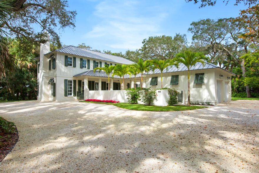 Nestled among ancient live oaks on a sandy lane in old Riomar, is a simply exceptional new build, designed by Peter Moor of Moor, Baker & Associates Architect (2022 Palladio Award Winners). This fabulous 4 bedroom, 3.5 bath home has all the features you expect from a new residence:   standing seam metal roof, impact rated windows and doors, custom crafted cabinetry, kitchen table, trims and moldings, vaulted/beamed 2 story ceiling, Chinese Chippendale bannisters, custom chandeliers and sconces and top-notch appliances that make living sophisticated, yet easy.
Guests enter into a paneled foyer with a bench and sports closet. Enjoy the light in the great room from the paned clerestory windows, and the whimsical Juliet balcony from the upstairs bedroom.  The kitchen has colorful backsplash with tropical tiles. A bright and cheery sunroom from the kitchen brings the outside indoors on this .66-acre parcel.