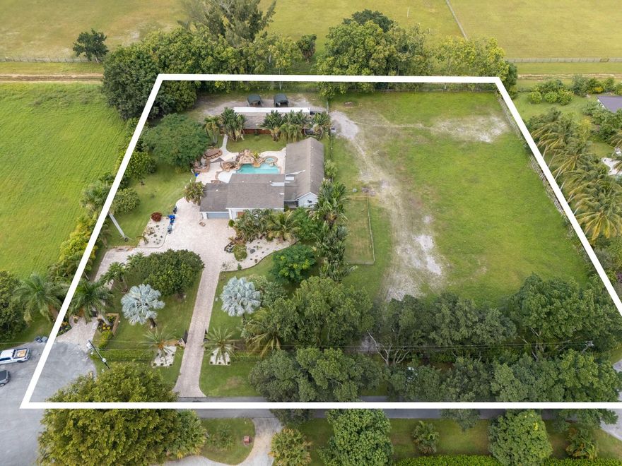 Rare 2.5-acre AG-exempt property in Boca Raton’s coveted Horseshoe Acres offering low taxes, privacy, and exceptional upside. The 4-bedroom, 3.5-bath residence features impact windows and upgrades throughout. Fully fenced with dual gated entrances, the property feels like a private compound. Outdoor amenities include a resort-style pool with waterfall, slide, spa, and swim-up bar. Ideal for horse lovers, families, investors, or developers seeking one of Central Boca’s rare large-acreage opportunities. (SEE ADDITIONAL REMARKS)