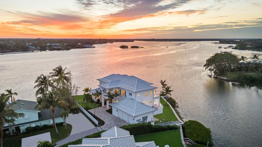 Experience the epitome of waterfront living with this dreamy sunset lover's retreat. Situated serenely along the tranquil Jupiter Inlet, this property captivates with its sprawling 265 feet of aqua-blue waterfront point lot, offering unparalleled views of the majestic Loxahatchee River. Crafted in exquisite West Indies design, this two-story new construction masterpiece showcases meticulous CBS construction from top to bottom, fortified with Icynene insulation and Acoustiblok installation. Enhanced with high-impact windows and doors, your peace of mind is assured.

Within, discover the convenience of two kitchens, two living rooms, two laundry rooms and with SONO surround sound speakers. Step outside to indulge in the heated and chilled pool and spa, where every moment is framed by breathtaking views of the crystal-clear waters. Boating enthusiasts will delight in the newly constructed seawall and private dock, ready to accommodate multiple vessels.

Embrace every sunset with open arms, as this remarkable location invites you to relish uninterrupted panoramas across the Loxahatchee River. Jupiter's reputation for world-class fishing, boating, paddleboarding, kayaking, and an array of recreational pursuits awaits, ensuring a lifestyle of unparalleled leisure and adventure.