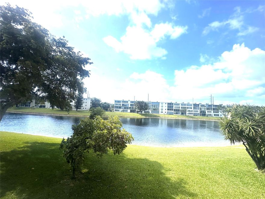 Welcome home to this cozy & bright 1 bedrm, 1 bath condo w/ a stunning VIEW OF THE LAKE! The spacious liv area has an open kit w/white appl (incl. dishwasher), an island for extra cntr space & storage & beautiful lam wood flrs. The updated bathrm has tiled walls, tub/shower & glass shower doors. Unit comes partially furnished. Enjoy a cup of coffee while overlooking the beautiful water view on your lovely encl patio w/sliding plexi glass windows & roll up shutters. New AC & bldg. has a NEW ROOF & 2 elevators! Gated comm w/24 hr sec, courtesy bus, pools, tennis, pickle ball, putting green, cafe, state-of-the-art Clubhouse w/fitness cntr, billiards, theater, free movies, classes, clubs, ping pong,  Minutes to shopping, restaurants, beach & hwys. Enjoy South Florida living! ASSOC. CLAIMS 55+