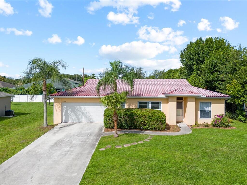 Incredible value in Port Saint Lucie! Calling all first-time homeowners! Spacious 3 bedroom, 2 bath, 2-car garage home featuring a split floor plan with vaulted ceilings and tile flooring throughout. The large living area opens to an 8' x 20' screened patio and a private, fenced backyard. Built with strength and durability, this home includes fixed industrial exterior wall slabs, aluminum roof trusses, a metal barrel roof, and hurricane shutters. This home is solid! Primary suite offers a walk-in closet. All bedrooms include ceiling fans. Conveniently located close to shopping, dining, schools, and major highways. Water heater replaced in 2020, A/C 2023. Home is ready for updates and personal touches! Come and make it all yours today!